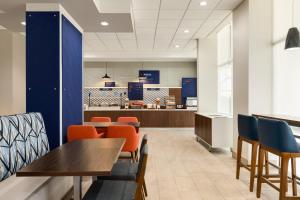 a cafeteria with tables and chairs and a kitchen at Holiday Inn Express Fort Lauderdale Airport South by IHG in Dania Beach