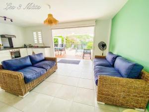 Una sala de estar con dos sofás y una cocina. en Bungalow bord de mer, en Le Robert