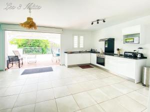 cocina grande con armarios blancos y patio en Bungalow bord de mer, en Le Robert