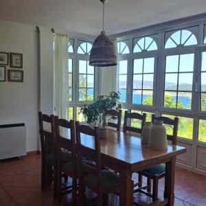 a dining room with a table and chairs and windows at Casa Teresa in Laxe +34 photos