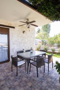 a table and chairs on a patio with a ceiling fan at Daphne Villas in Kriopigi