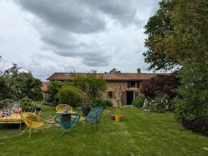 a yard with chairs and a table in front of a house at Le refuge du Jardinier in Abzac +49 photos