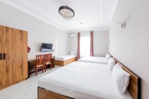 a white bedroom with a bed and a desk at Centrum Hotel Tashkent in Tashkent