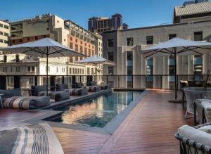 a pool on the roof of a building with umbrellas at The Cozy Luxe Apartment in Cape Town