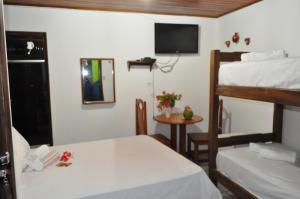 a room with two bunk beds and a table with a small table at Amendoeira Hotel da Vila in Morro de São Paulo