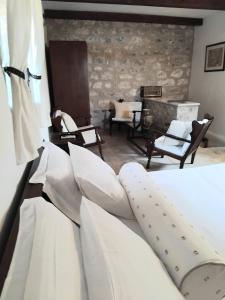 a bedroom with a white bed and a stone wall at Mani Fort Charabos in Stavríon