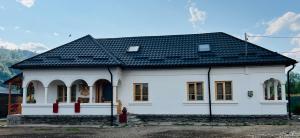 a white house with a black roof at Conacul Perla Bratiei in Cîndeşti