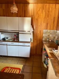 cocina con paredes de madera, armarios blancos y fregadero en Seventies, en Le Verdon-sur-Mer
