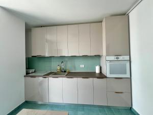 a kitchen with white cabinets and a sink at AVIATORII Modern Escape Apartment in Constanţa