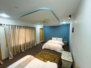 a bedroom with two beds and a blue wall at Creek Villa Skardu in Skardu
