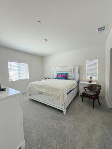 Un dormitorio blanco con una cama y una silla. en ALTA Elk Grove Stylish Retreat, en Elk Grove