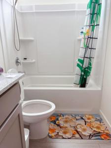 Un baño con inodoro y cortina de ducha con flores en el suelo. en ALTA Elk Grove Stylish Retreat, en Elk Grove