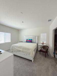 Un dormitorio blanco con una cama y una silla. en ALTA Elk Grove Stylish Retreat, en Elk Grove