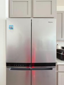 Un refrigerador de acero inoxidable en una cocina con gabinetes blancos. en ALTA Elk Grove Stylish Retreat, en Elk Grove