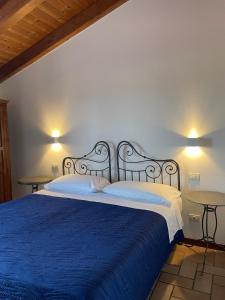 a bedroom with a bed with blue sheets and two tables at Agriturismo La Rondinella in Dozza