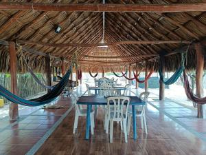Un comedor con mesa y sillas y hamacas. en Hostal CQ Camarones, en Camarones