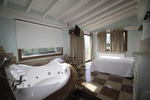 a bathroom with a bath tub and a bed at Hosteria,restaurante,cafeteria Los Abetos in Villanueva de la Peña
