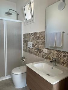 Un baño con lavabo, inodoro y espejo. en Villa Gallieco, en Noto