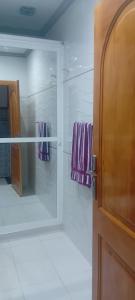 Un baño con puerta de cristal con toallas moradas. en historical Spanish influence flat, en Larache