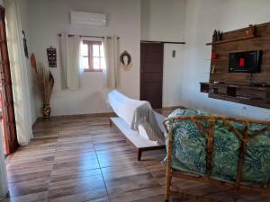 ein Wohnzimmer mit Sofa und Fernseher in der Unterkunft Casa Vista Baepi - Estilo Boho, Mais Streaming a 1,5km da Balsa in Ilhabela
