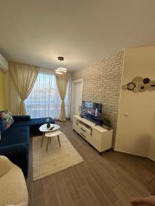 a living room with a blue couch and a tv at Sinemorets Blue apartments in Sinemorets