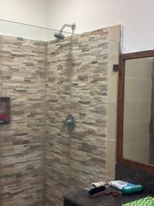 a shower in a bathroom with a stone wall at The Bird House in Ukunda Airport