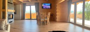 a dining room with a table and a tv on the wall at Cicha Ostoja in Czarny Dunajec