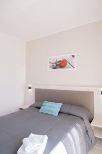a white bedroom with a bed with a red object on it at Carrera Living Family Apartments in Borgomanero