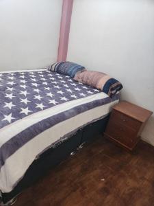 ein Bett mit einer Decke mit amerikanischer Flagge und einem Nachttisch in der Unterkunft Departamento Esmeralda in Chota