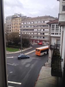 a bus and a car on a city street with buildings at Pensión Hedrass in Santiago de Compostela