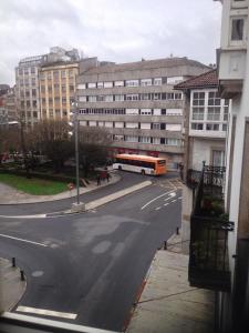 a bus driving down a city street with buildings at Pensión Hedrass in Santiago de Compostela +12 photos