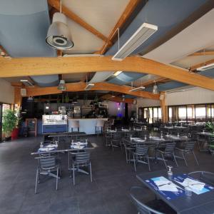 una sala da pranzo con tavoli e sedie e una cucina di 155- Joli Mobilhome 4 Pers 2 chambres Clim Tv Wifi Camping 5 étoiles a Houlgate