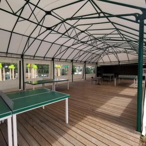 un campo da tennis con due tavoli da ping pong in un padiglione di 155- Joli Mobilhome 4 Pers 2 chambres Clim Tv Wifi Camping 5 étoiles a Houlgate