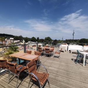 una terrazza con tavoli e sedie su una barca di 155- Joli Mobilhome 4 Pers 2 chambres Clim Tv Wifi Camping 5 étoiles a Houlgate