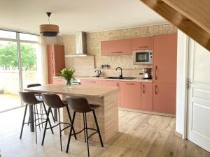 une cuisine avec des armoires roses et une table avec des tabourets dans l'établissement Entre Terre et Mer Meublé de tourisme 3 étoiles, à Colomby-sur-Thaon
