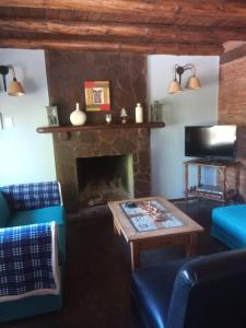 Una sala de estar con chimenea y una mesa. en Cabañas Las Lumas Esquel, en Esquel