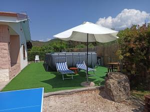 a patio with two chairs and an umbrella at Villa con piscina "Su Conte" in Alghero