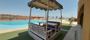 a bench with an umbrella next to a swimming pool at Porte Hotel in Az Za‘farānah