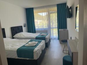 a hotel room with two beds and a window at Хотел Лилия in Rudozem