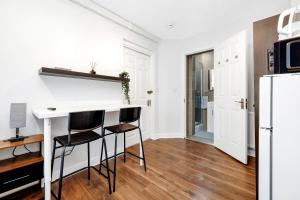 a kitchen with a white counter and two stools at The ground floor Green Oasis, near the station in London