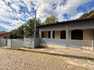 Ein weißes Gebäude mit einem Zaun an einer Straße. in der Unterkunft Casa Encanto de Lavras Novas - MG in Lavras Novas