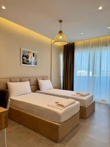a bedroom with two beds and a chandelier at Apartamente Antoni Shengjin2 in Shëngjin