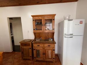 eine Küche mit weißem Kühlschrank und Holzschränken in der Unterkunft Casa Encanto de Lavras Novas - MG in Lavras Novas