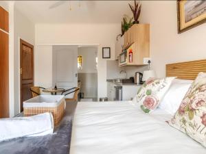 a bedroom with a white bed and a kitchen at Amalfi Place in Pretoria