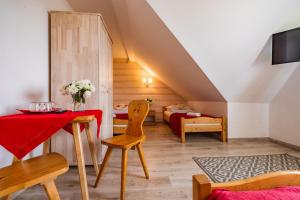 a living room with a table and a room with two beds at Pokoje Gościnne Góraleczka in Szaflary