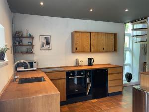 a kitchen with wooden cabinets and a counter top at The Barns Low Stott Park near Lake Windermere in Ulverston +16 photos