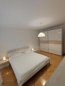 a white bedroom with a large bed and a chandelier at Apartman Doma in Livno +10 photos