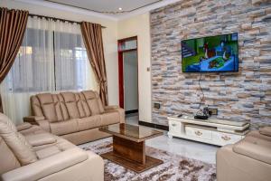 a living room with couches and a tv on a brick wall at Jengel Two Bedroom Apartments Entebbe 1 in Entebbe