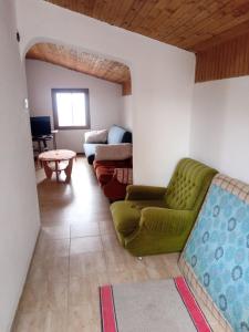 a living room with a green couch and a table at Braco apartmani Utjeha in Kravlja