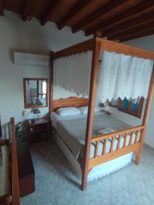 a bedroom with a wooden canopy bed with a mirror at Glaros Studios Agriolivadi Patmos in Patmos
